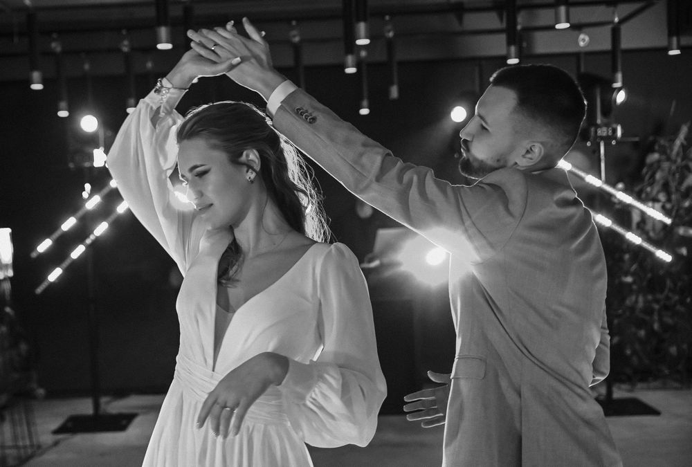 Black and white photo of couple dancing intimately at wedding reception.
