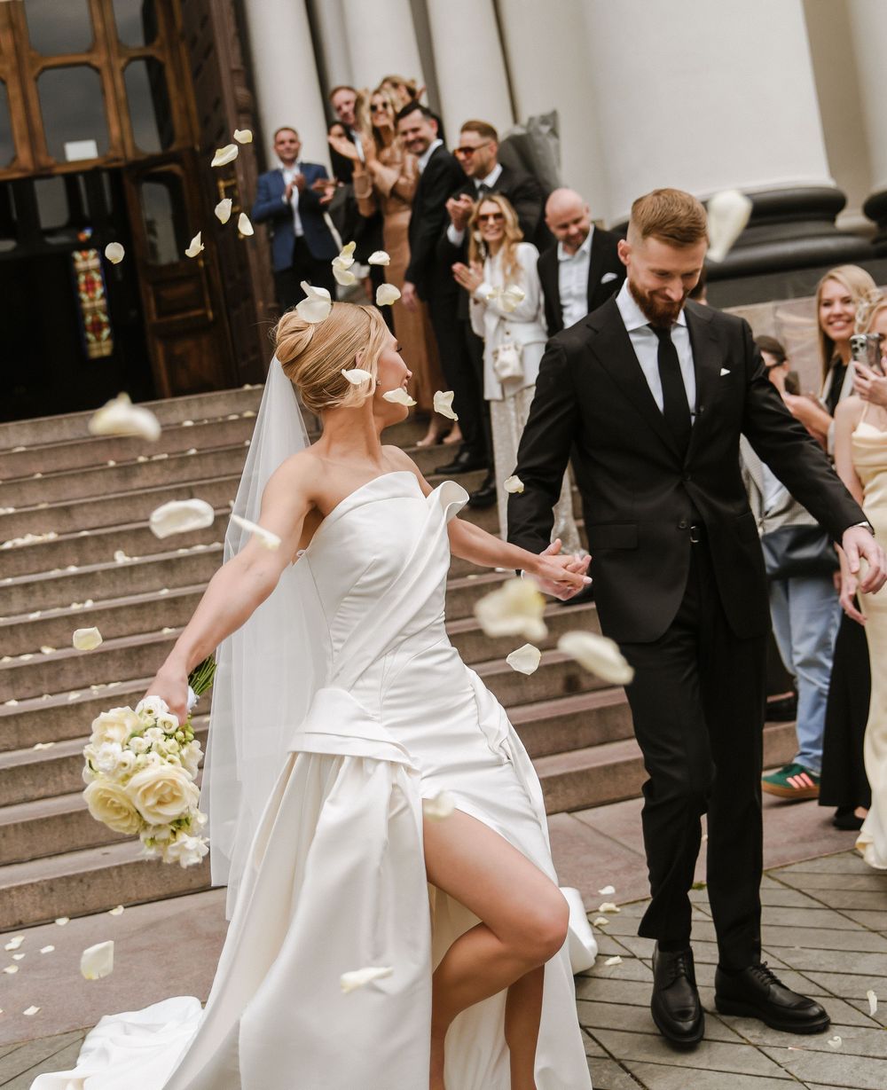 Newlyweds descend church steps while guests shower them with confetti in a joyful celebratory moment.