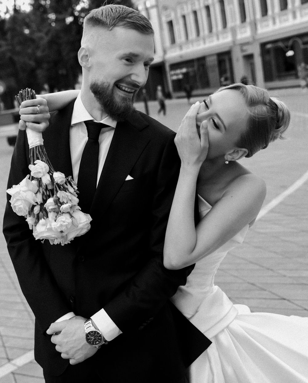 Black and white candid wedding photo capturing laughter and joy between newlyweds.