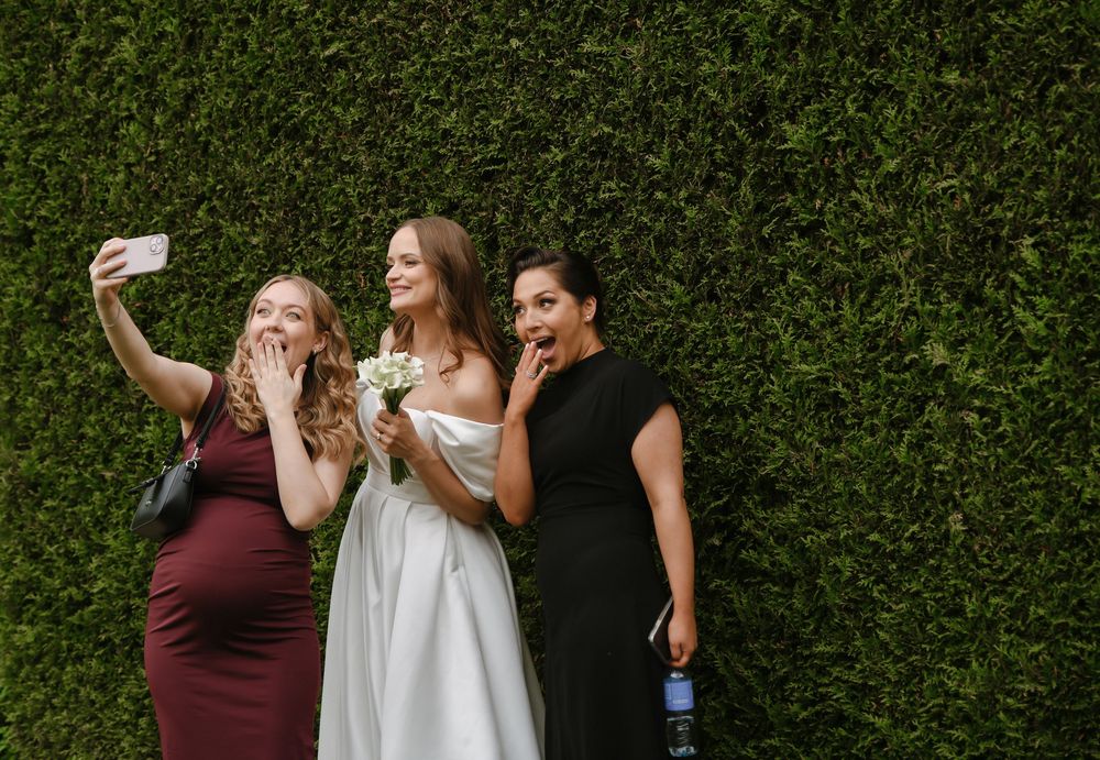 Celebratory moment captured against a lush green hedge backdrop as people raise their glasses in a toast.