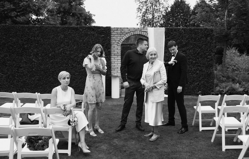 A panoramic black and white photo of an outdoor wedding ceremony setup with white chairs arranged on a lawn.