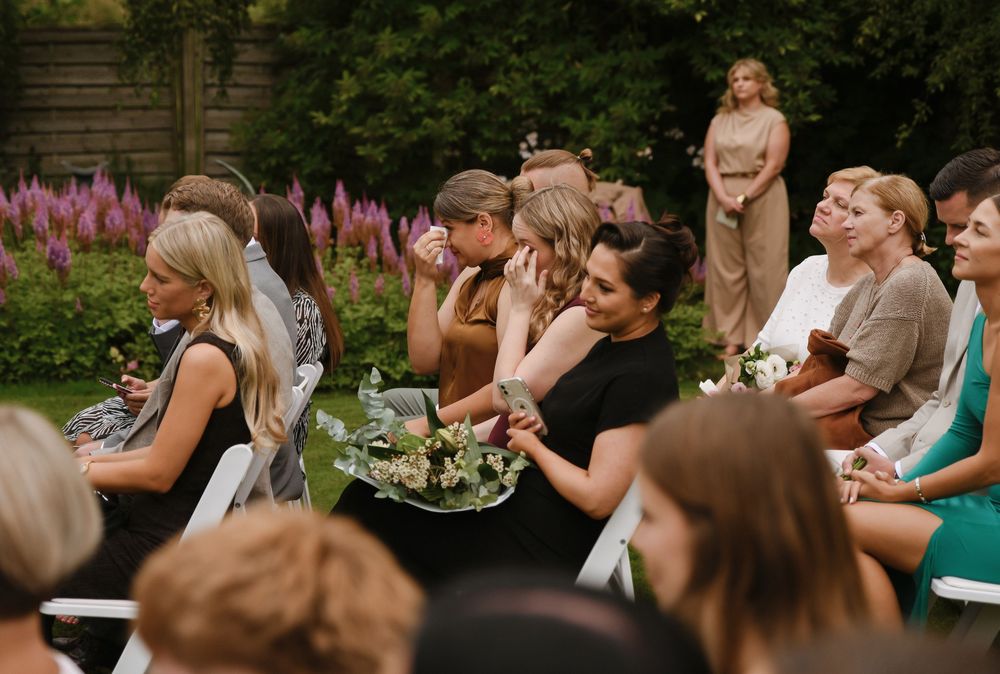 Wedding guests raise their glasses in a celebratory toast during an outdoor reception gathering.