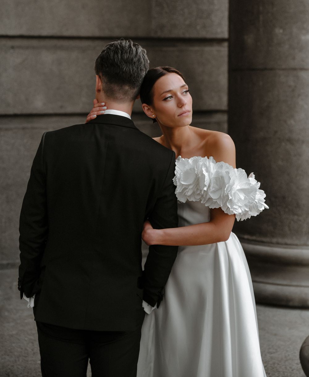 An intimate wedding portrait showing a tender moment between newlyweds against stone columns.
