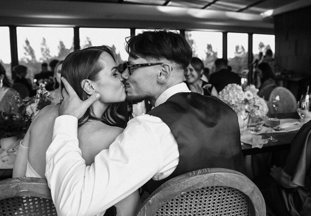 A romantic kiss shared between a couple at a restaurant in black and white vintage photography.