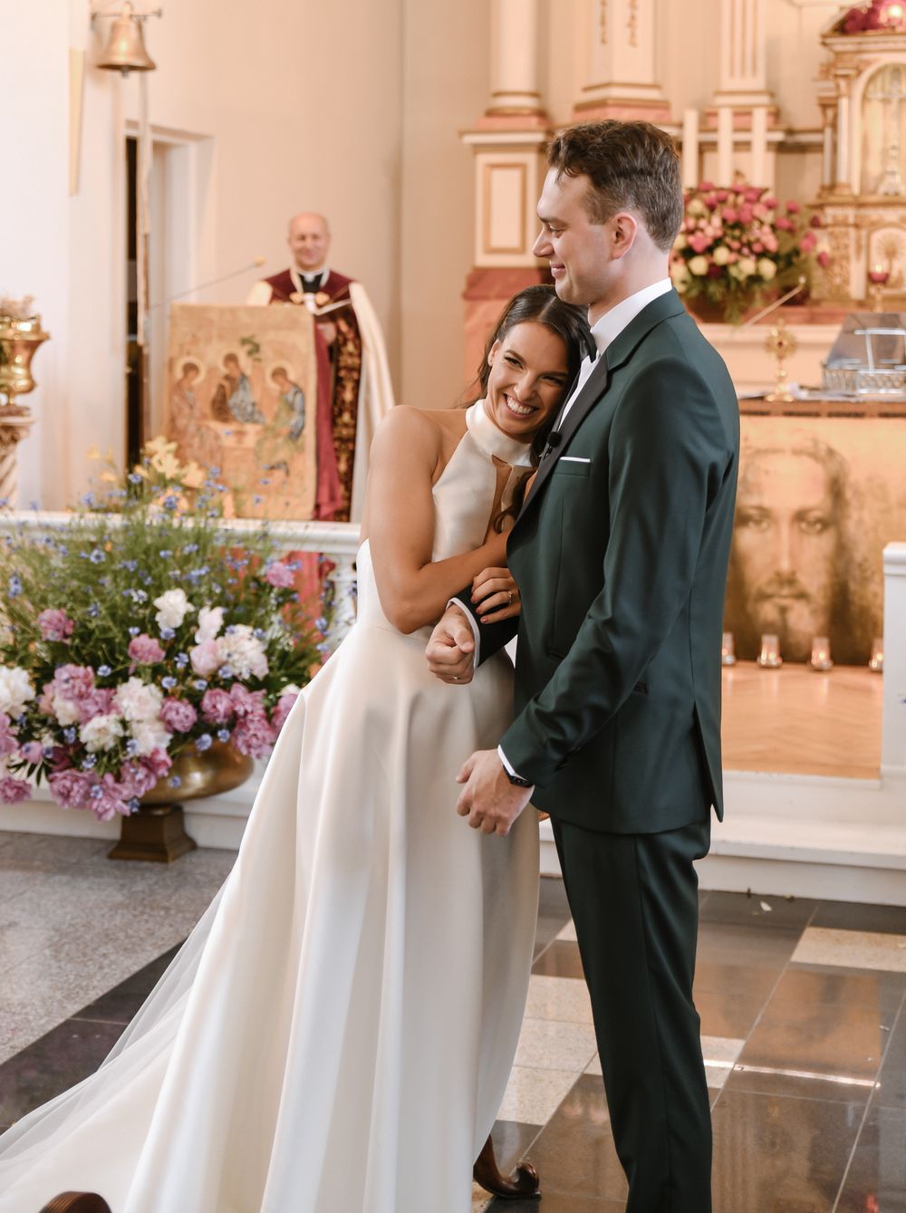 Couple shares emotional moment during ceremony in decorated church interior.