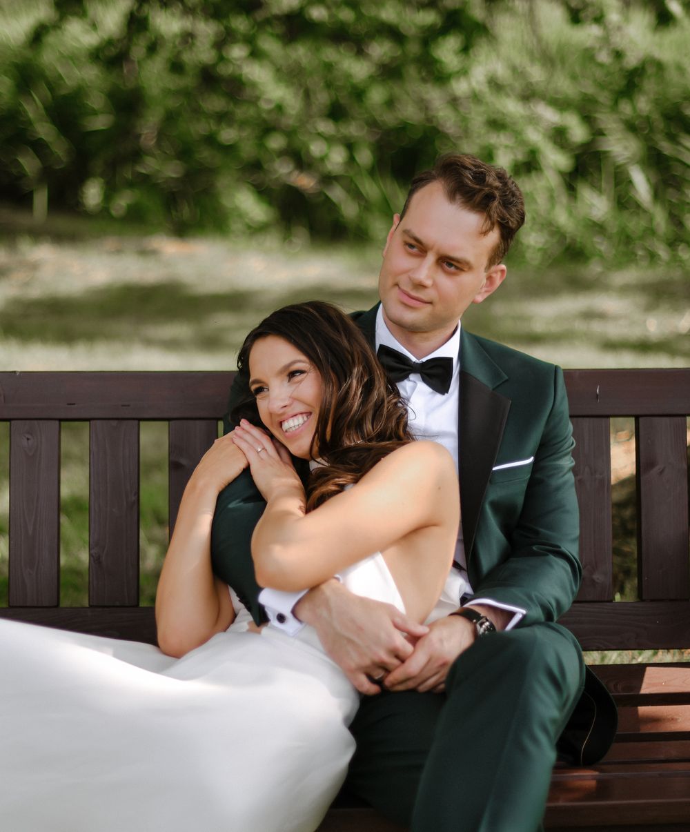 A couple shares an intimate moment on a wooden park bench.