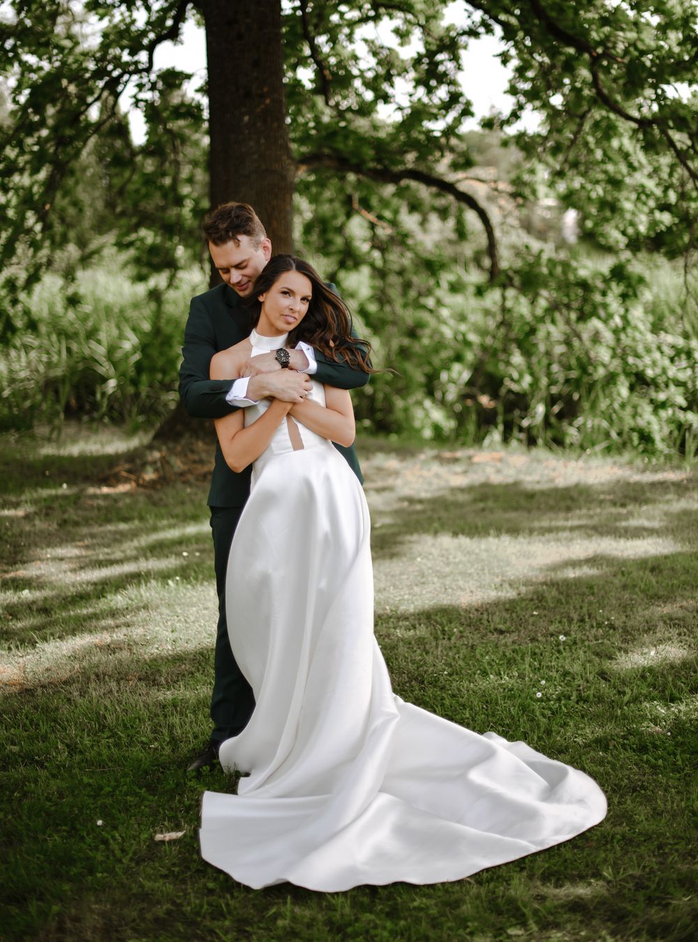 A couple embraces in a romantic moment on grassy grounds.