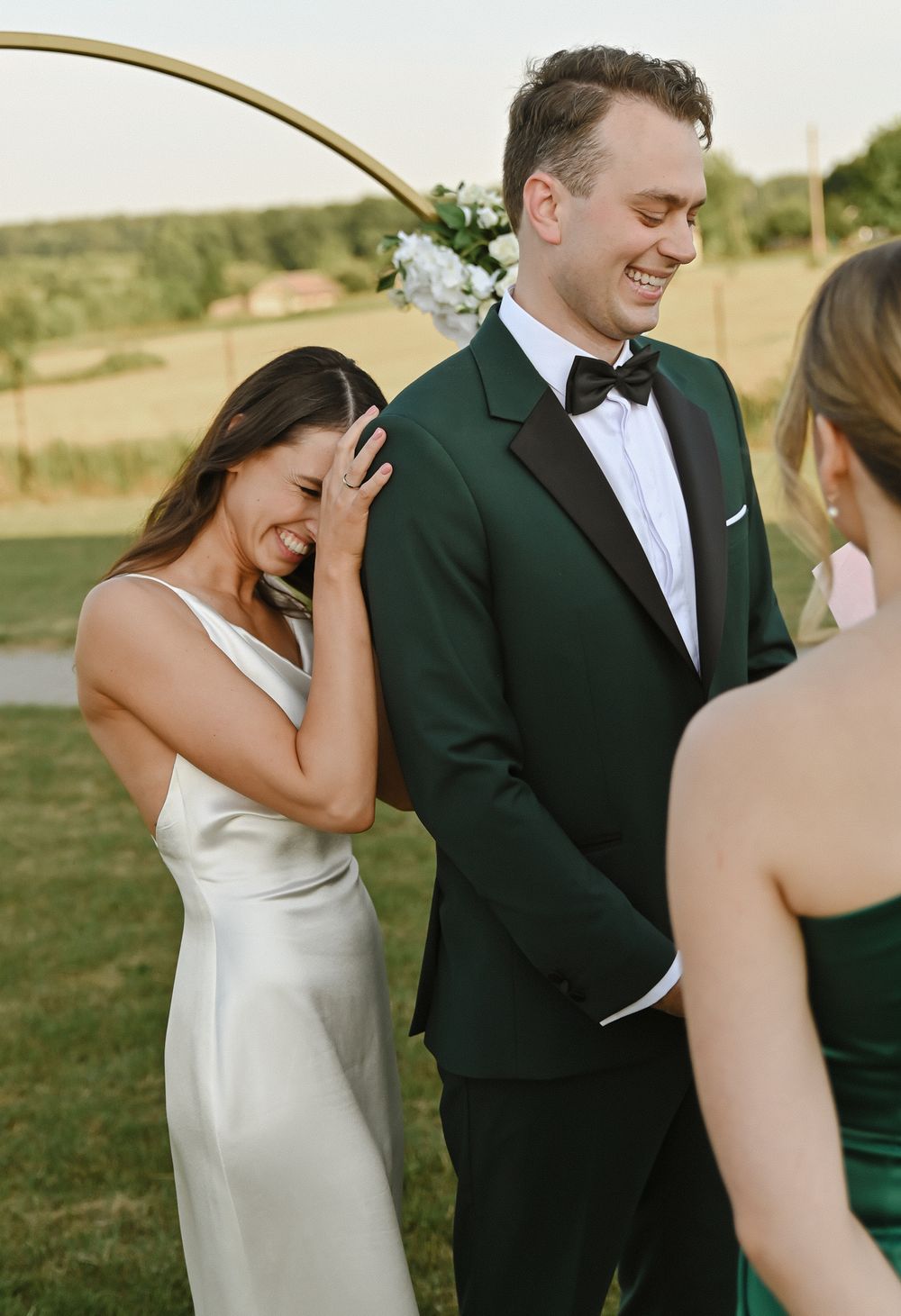 Wedding party members share joyful laughter during an outdoor ceremony.