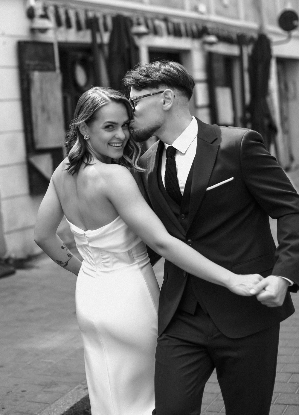 A joyful black and white wedding portrait of a couple embracing on a city street.