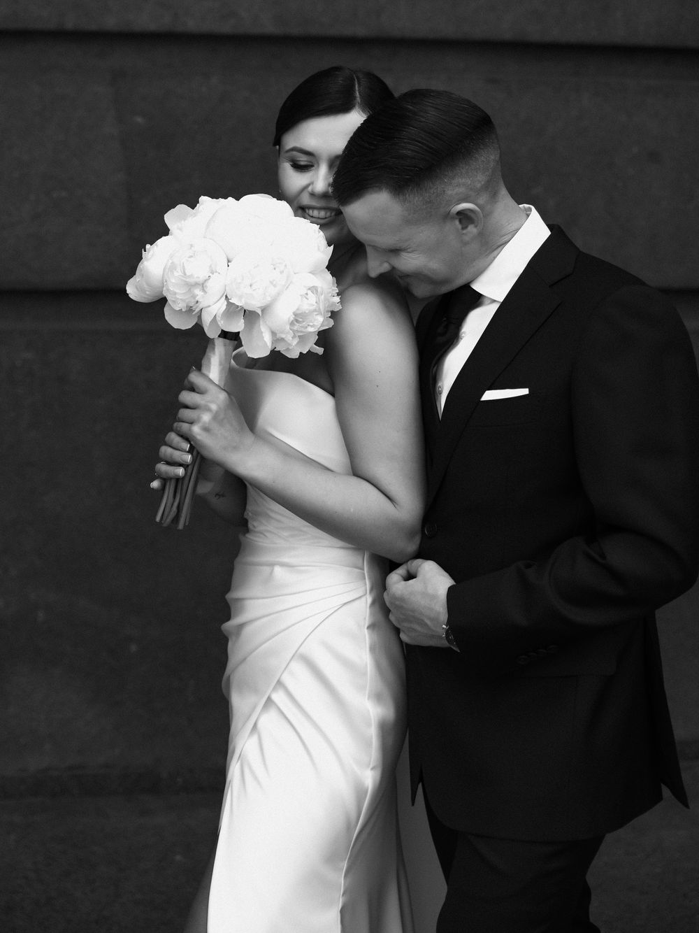 Romantic black and white wedding photograph featuring a strapless gown and white bouquet.
