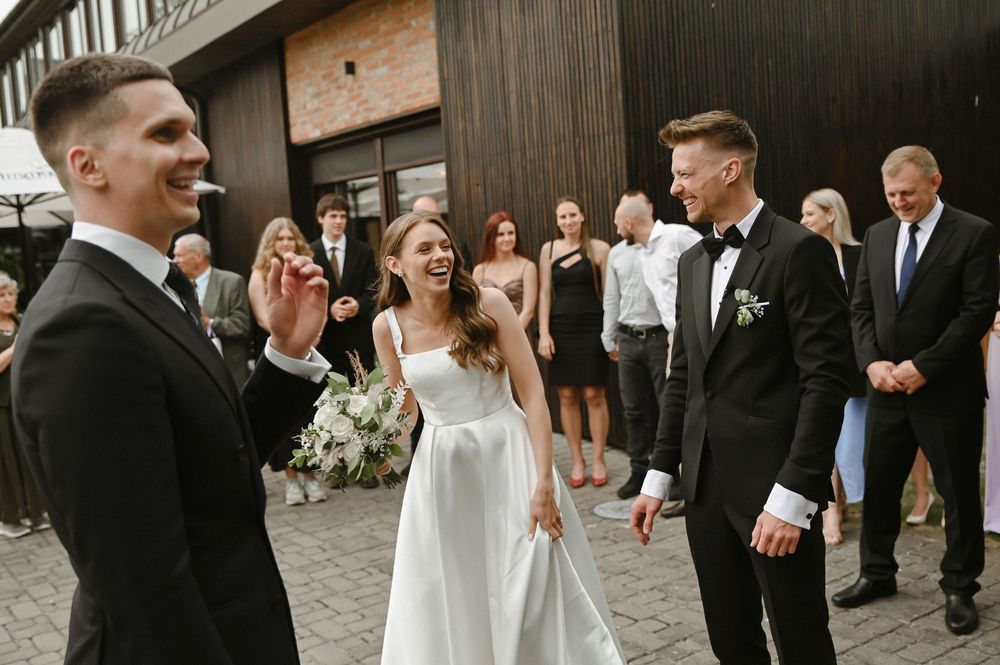 A happy couple shares a kiss during their wedding ceremony while guests look on at an outdoor venue.