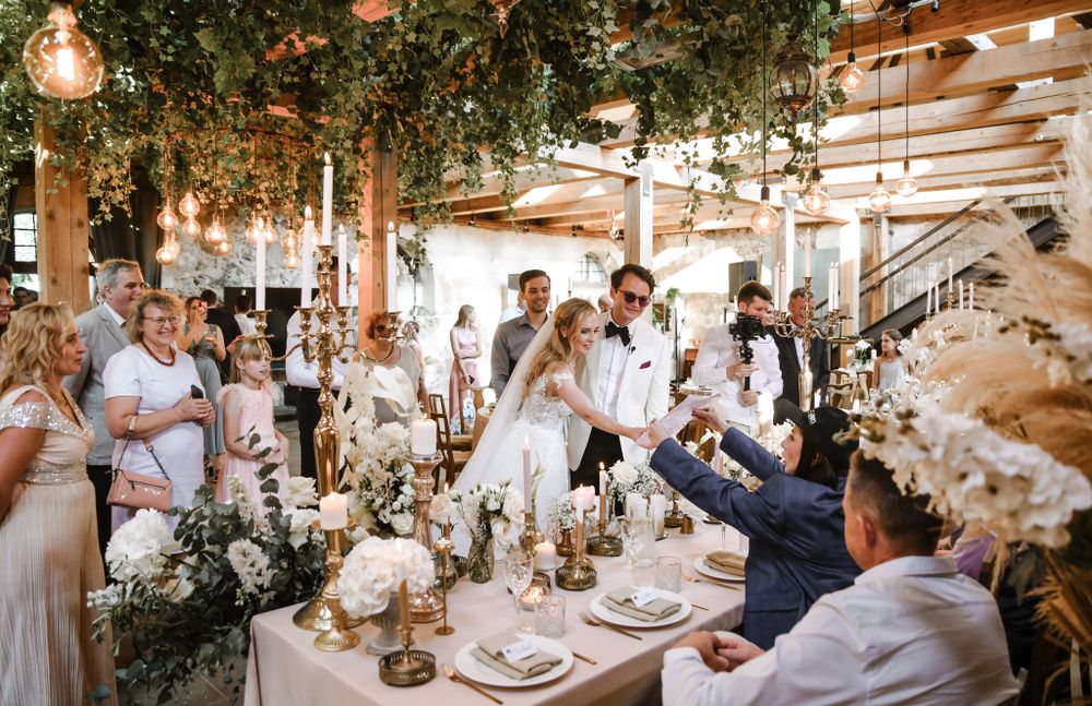 An elegant wedding reception decorated with hanging greenery and string lights in a rustic indoor venue.