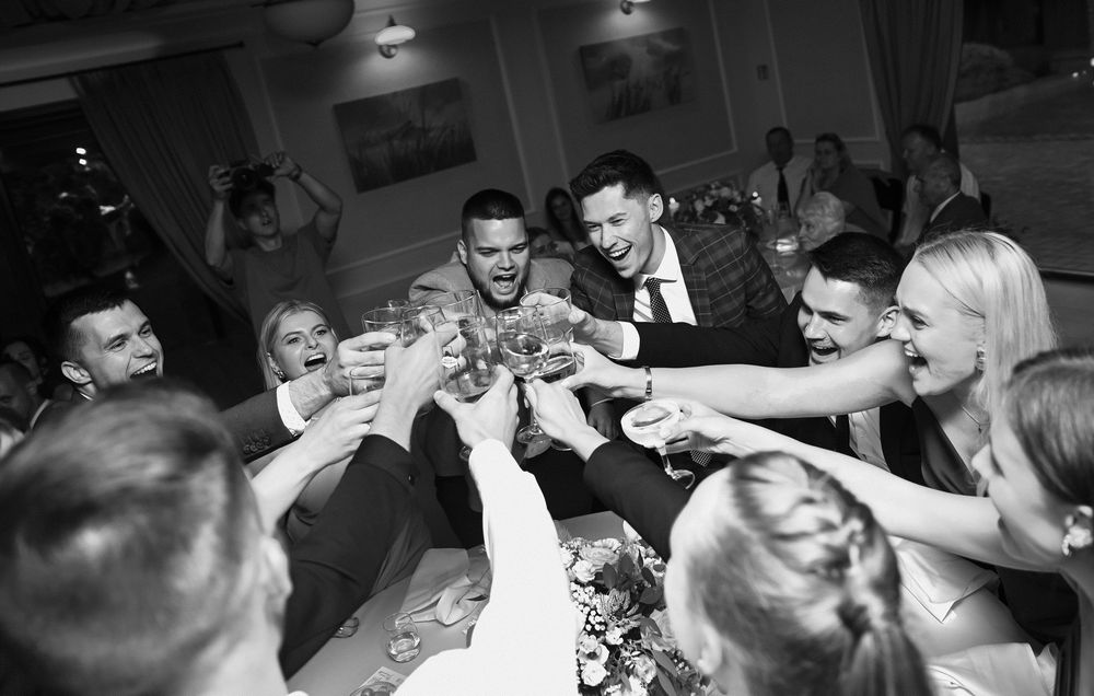 A series of black and white candid photos showing people laughing and socializing at what appears to be a dinner party.