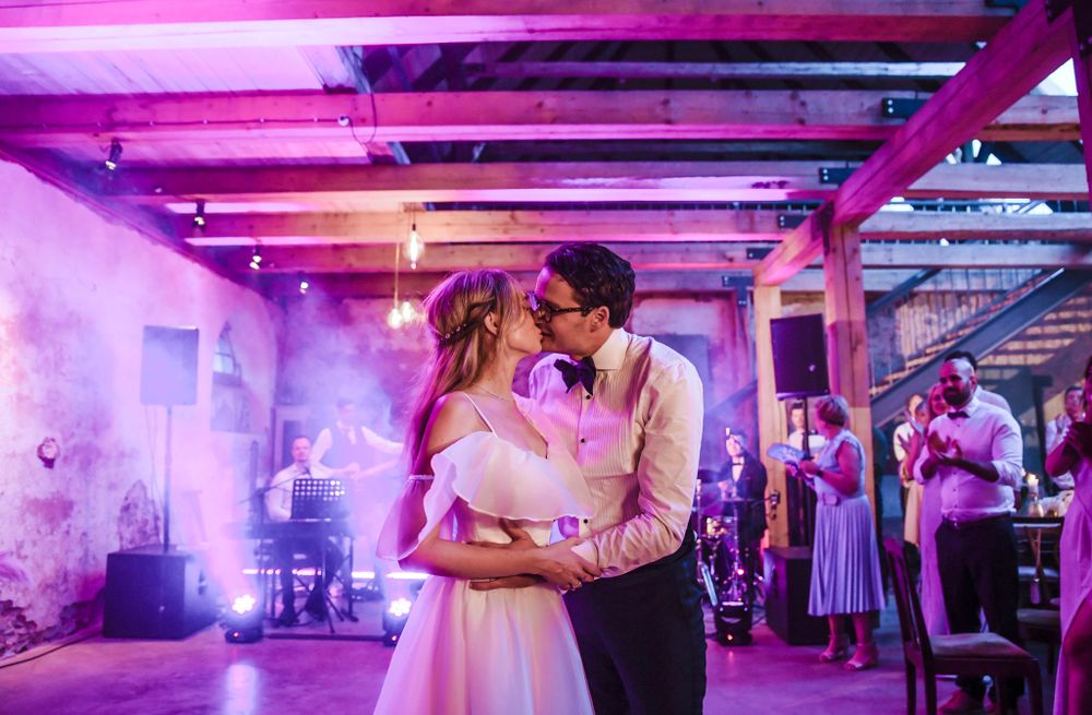 A couple shares an intimate dance moment under purple lighting at their wedding reception.