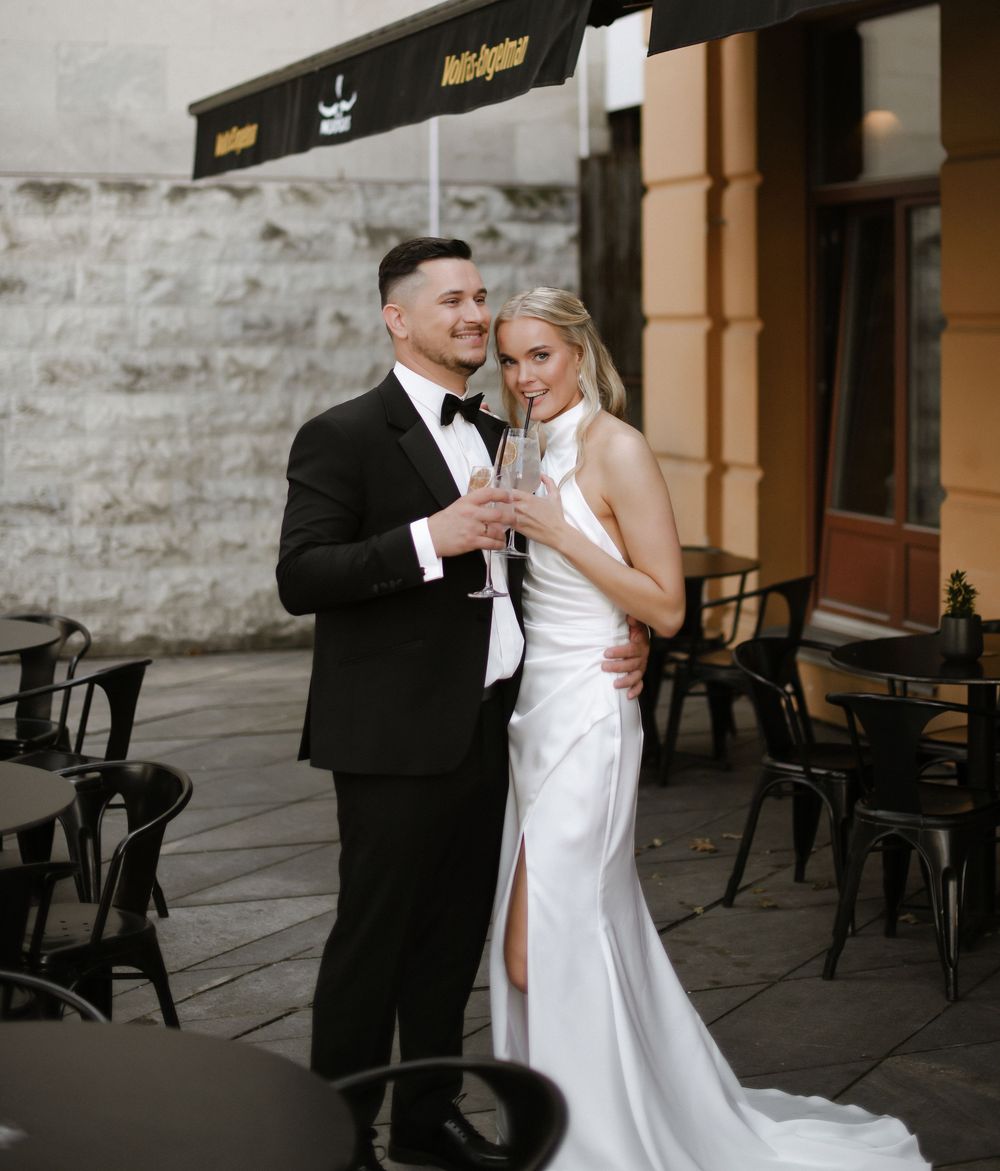 Romantic wedding couple shares an intimate dance moment on an outdoor terrace with black chairs in the background.