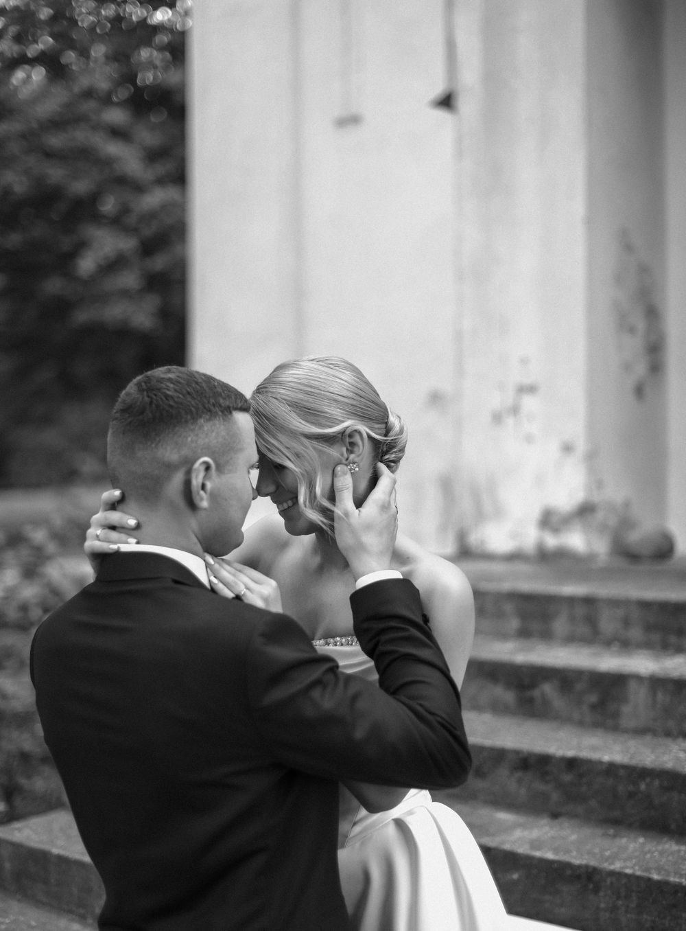 Black and white wedding photo sequence showing a romantic kiss between newlyweds in a classic outdoor setting.
