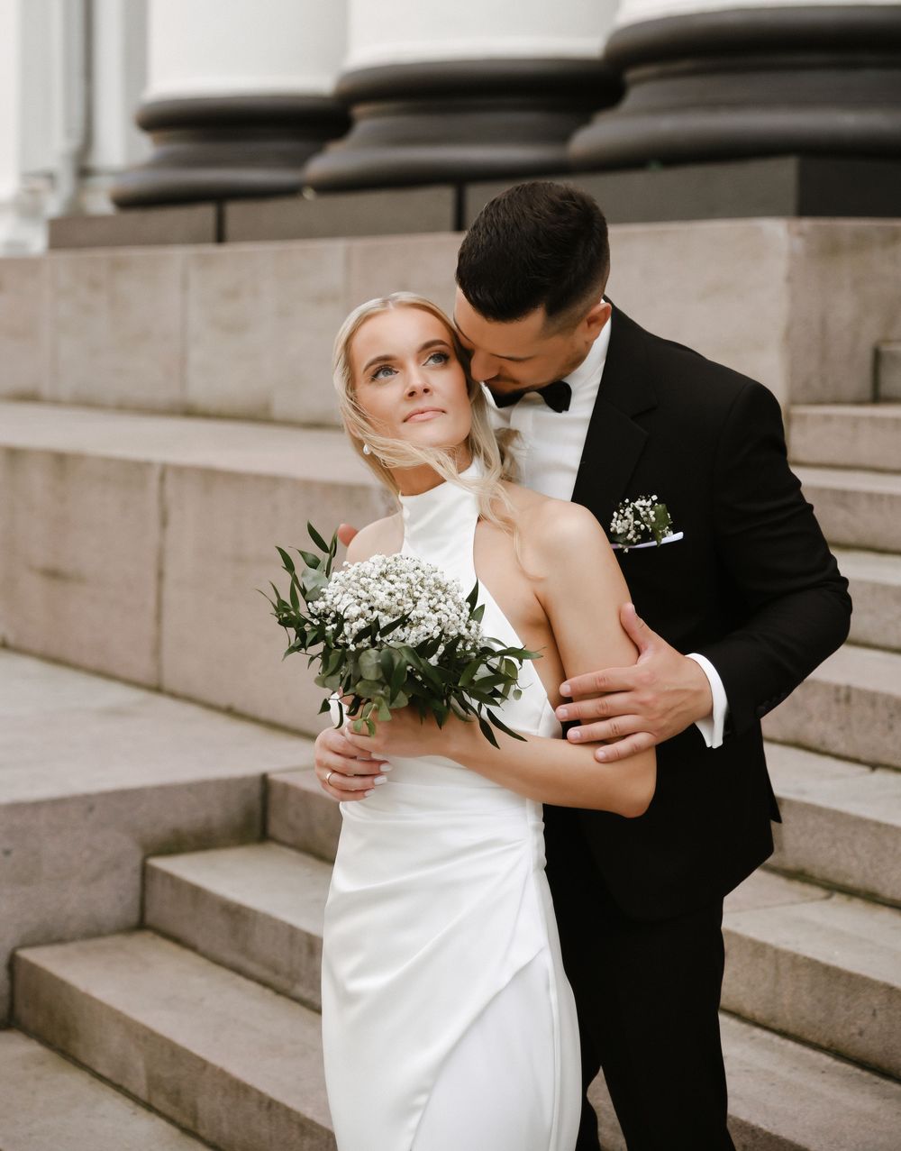 A romantic wedding couple embraces on stone steps in an elegant black and white outdoor photoshoot sequence.