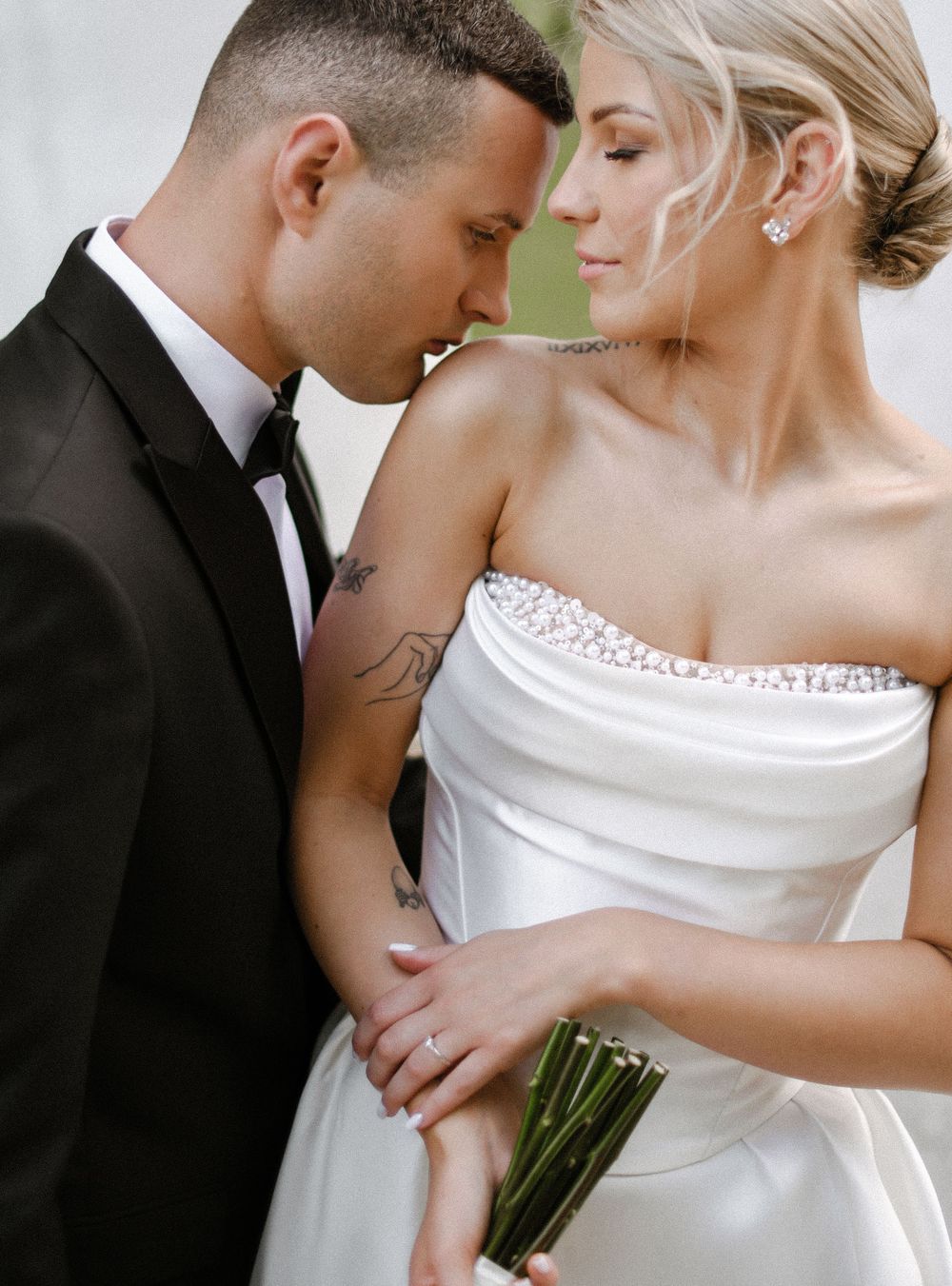 Romantic wedding couple in intimate poses wearing classic black tuxedo and elegant white bridal gown.