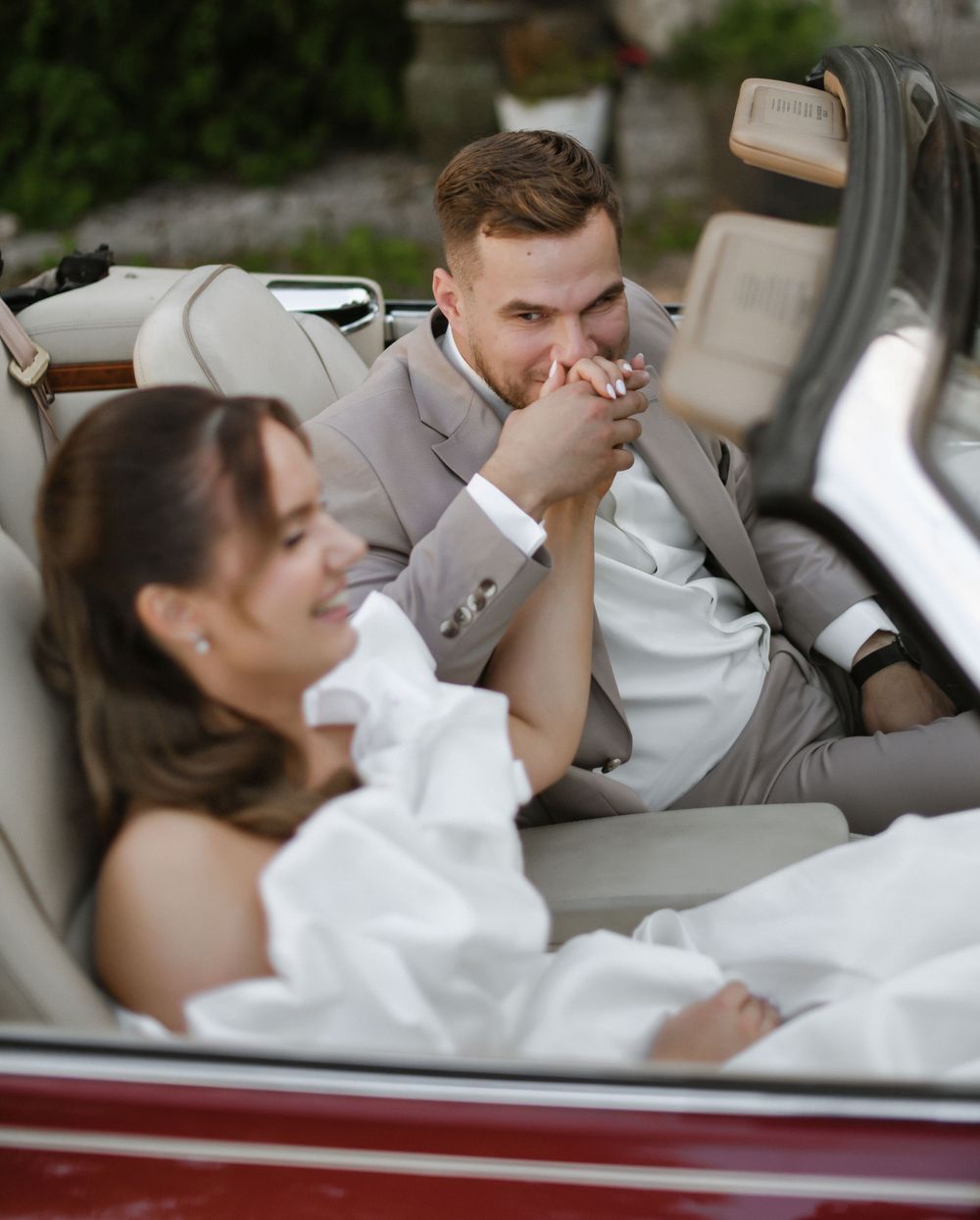 A couple relaxes together in a classic car, sharing an intimate moment in vintage style.