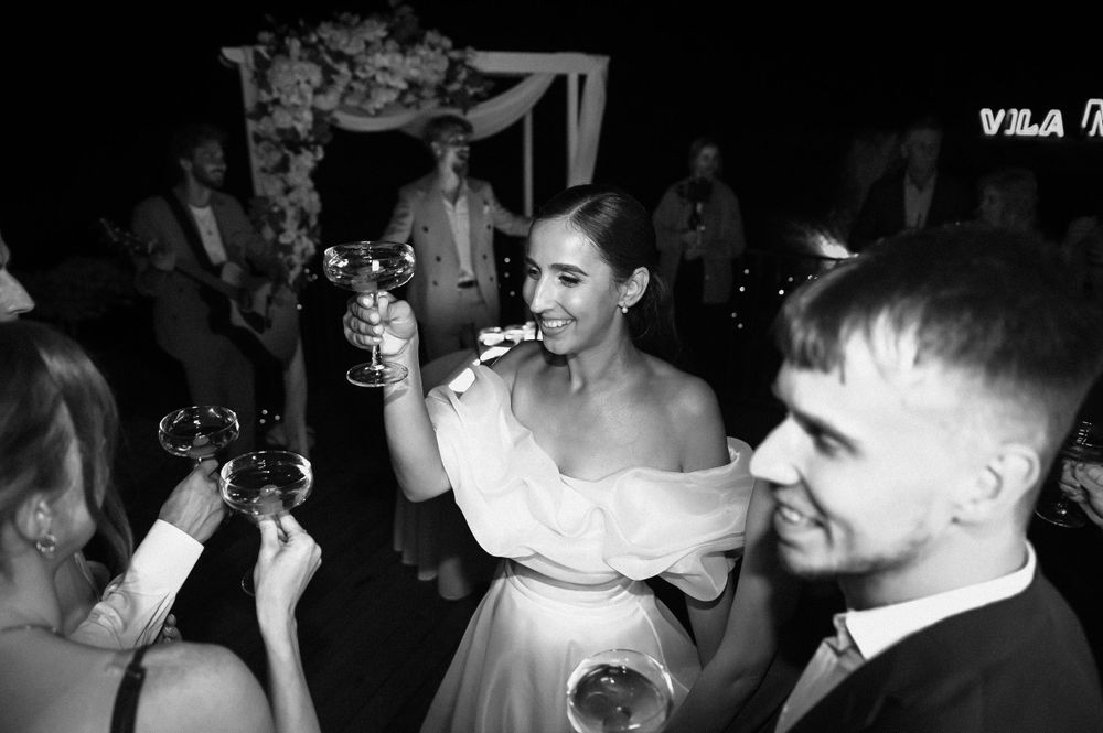 Wedding guests dancing at a reception under dim lighting and decorative elements.