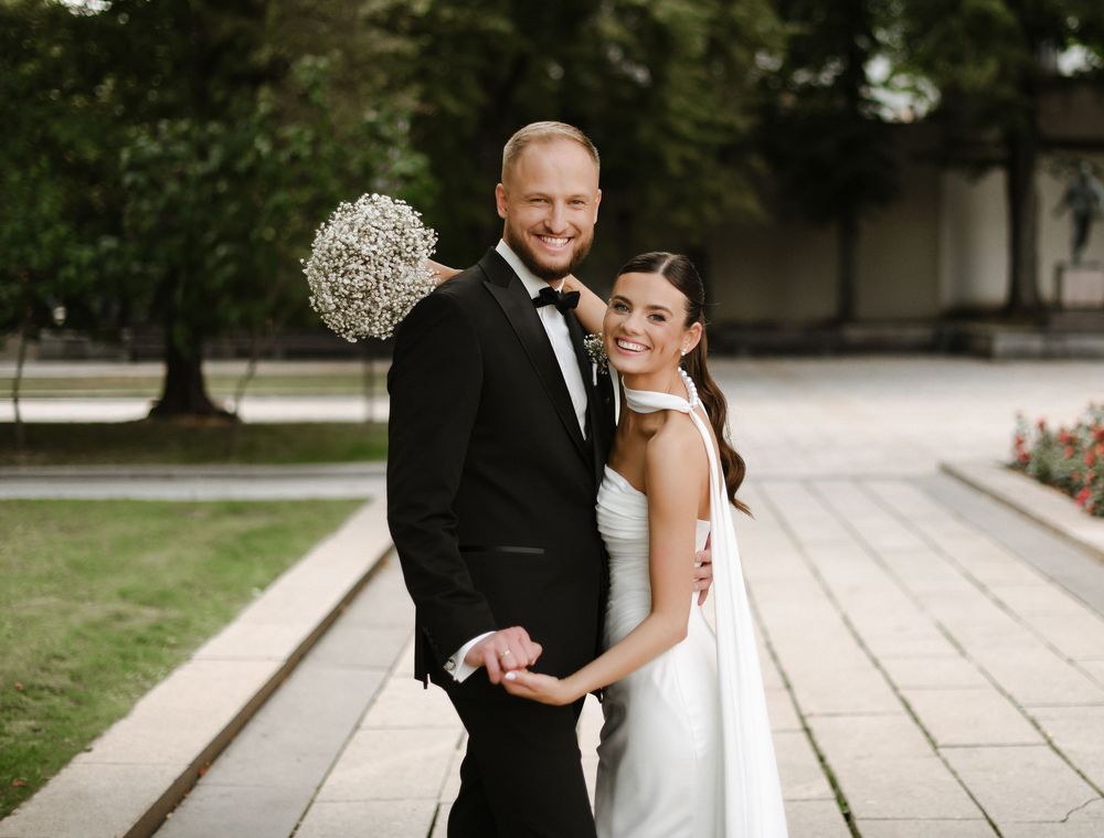 A bride and groom share a joyful moment together outdoors at their wedding ceremony.
