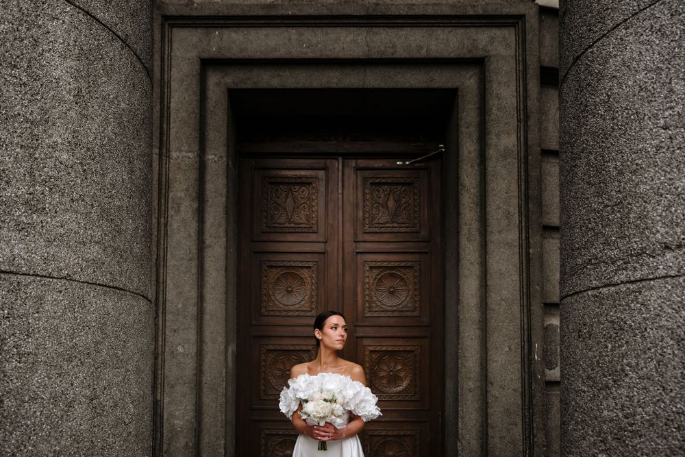 Dramatic bridal portrait in front of ornate wooden doors with stone columns.