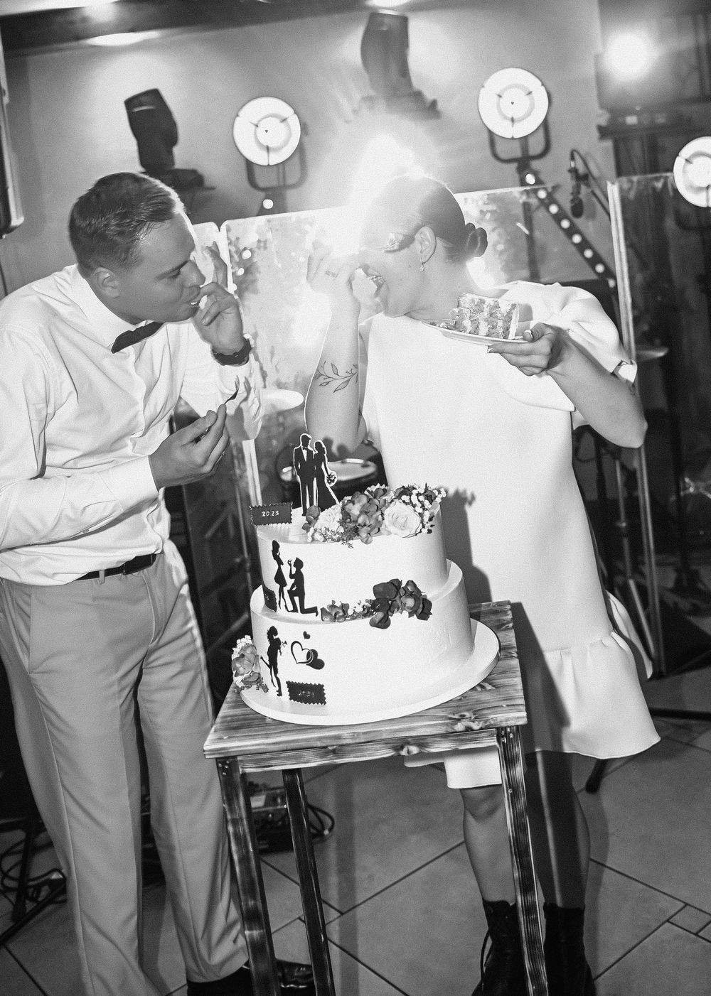 A black and white sequence showing a couple cutting their wedding cake together at a reception celebration.