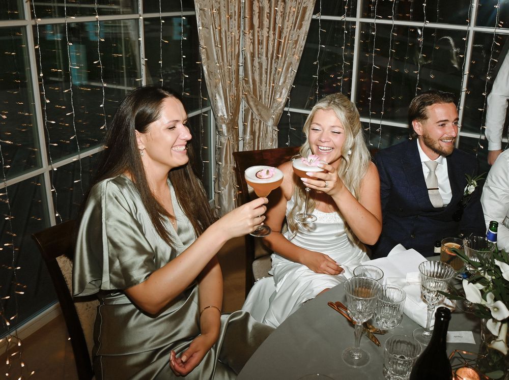 Wedding guests enjoy champagne toasts during an elegant reception celebration at a venue with string lights.