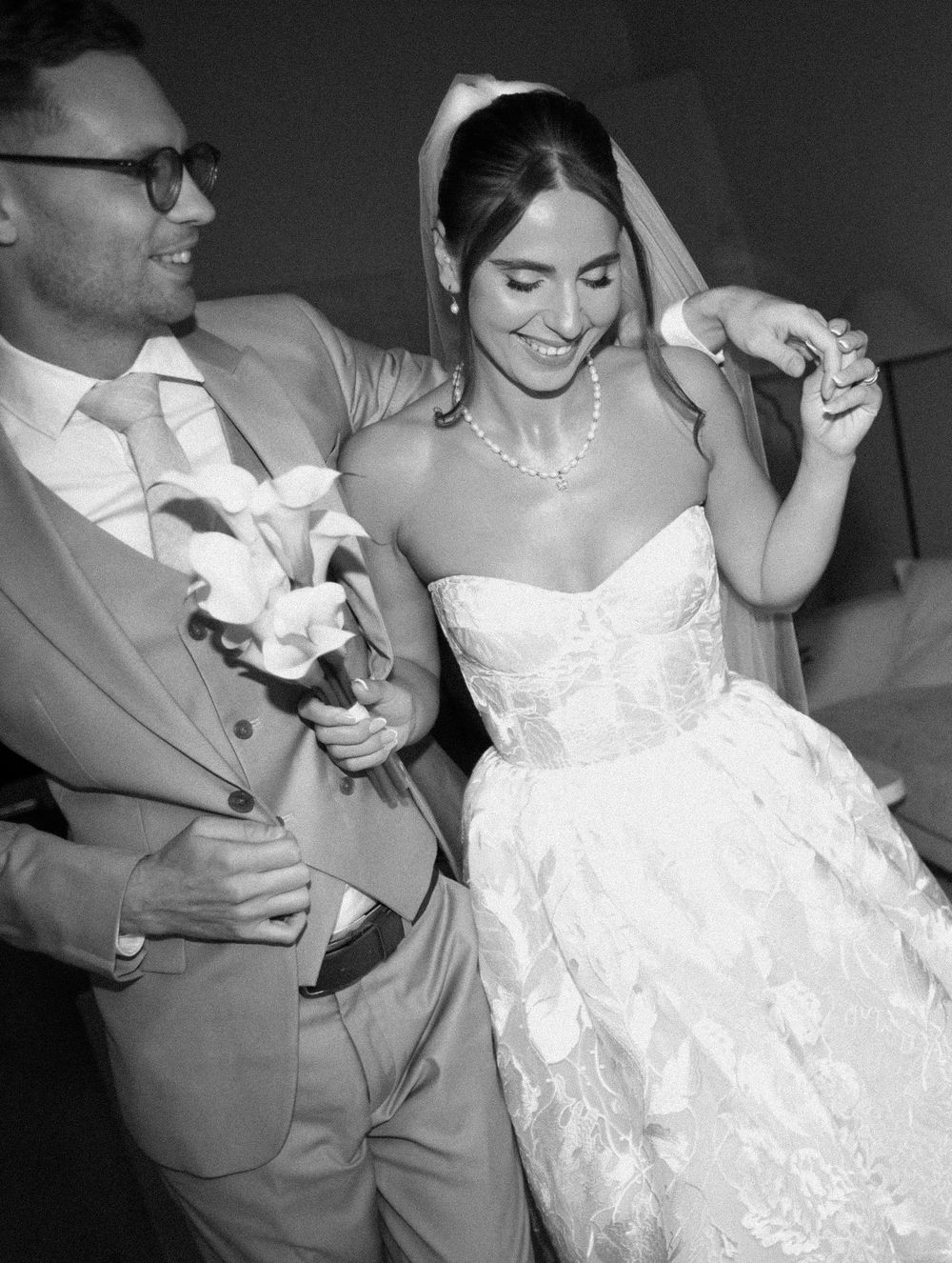 A newlywed couple shares an intimate dance together in black and white, with the bride wearing a beautiful white lace gown.