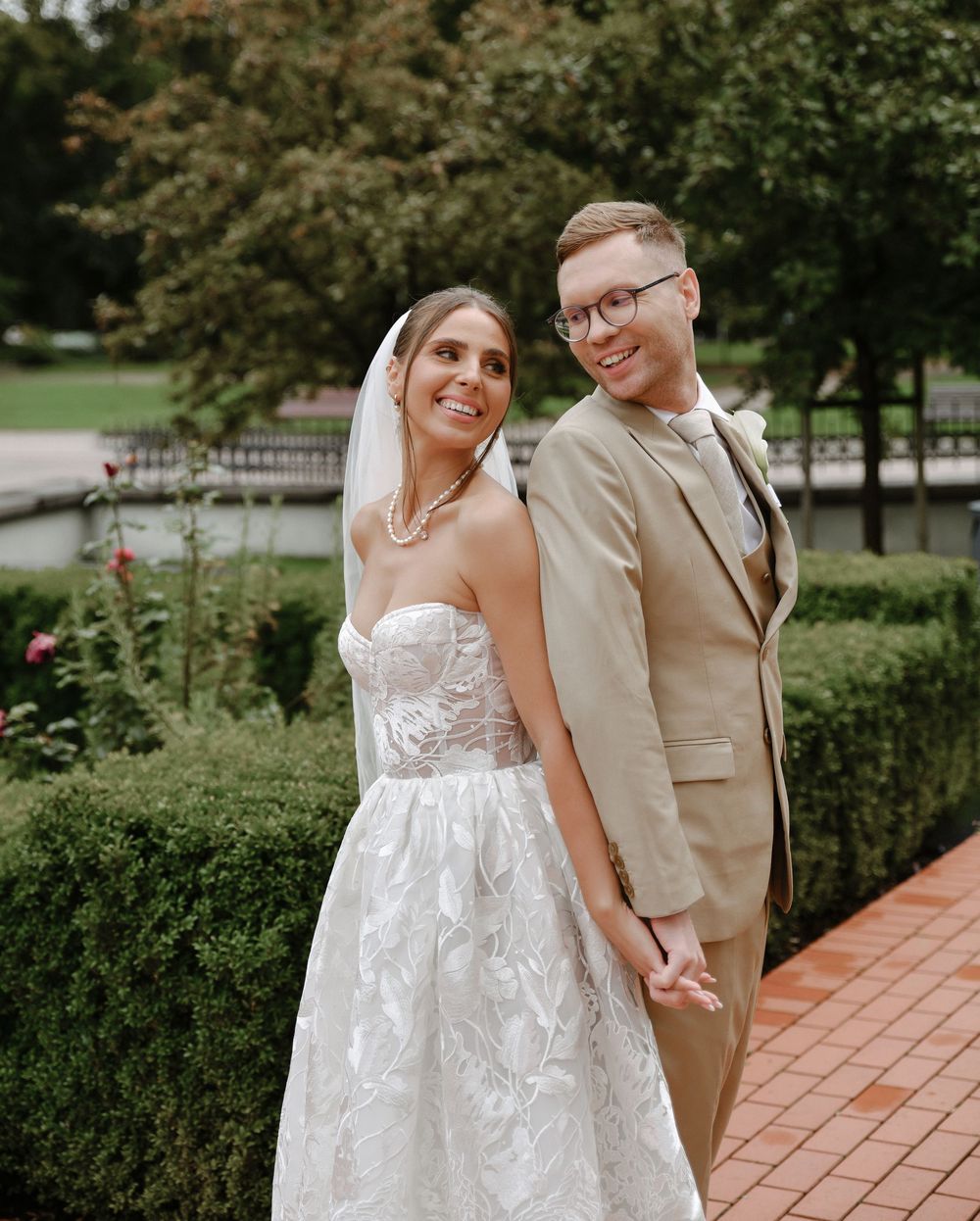 A couple in wedding attire share joyful moments together in a lush garden setting.