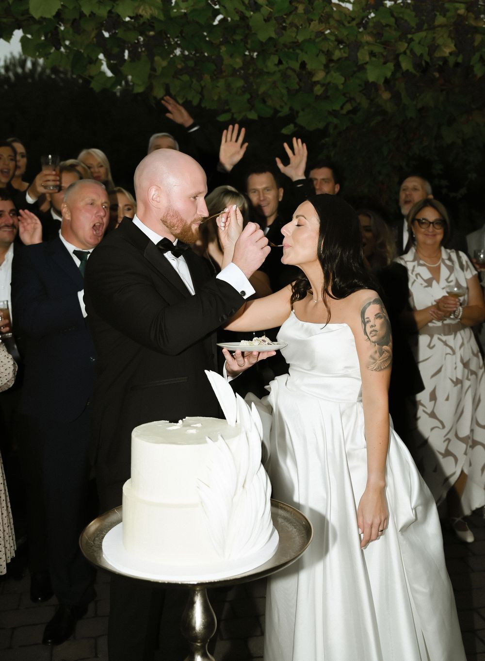 Wedding guests in formal attire dance together at an elegant outdoor reception celebration.