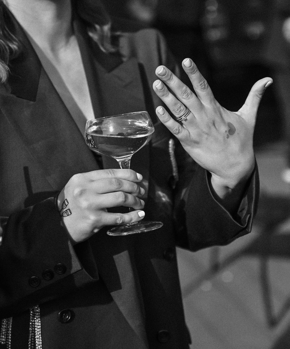 Black and white image showing hands holding wine glasses during a social gathering.