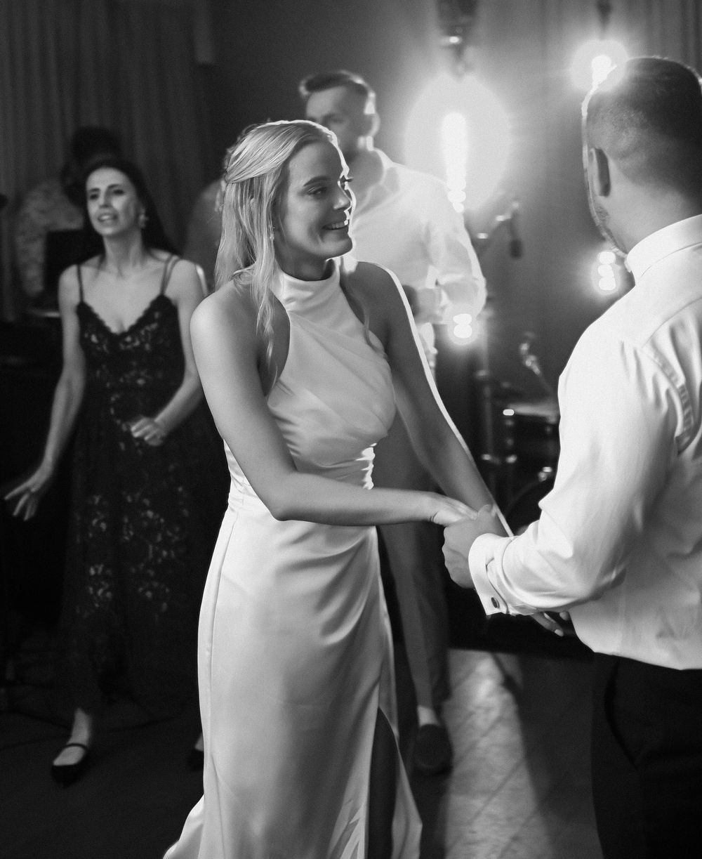 Black and white photos show couples dancing together at a wedding reception with dramatic lighting effects.
