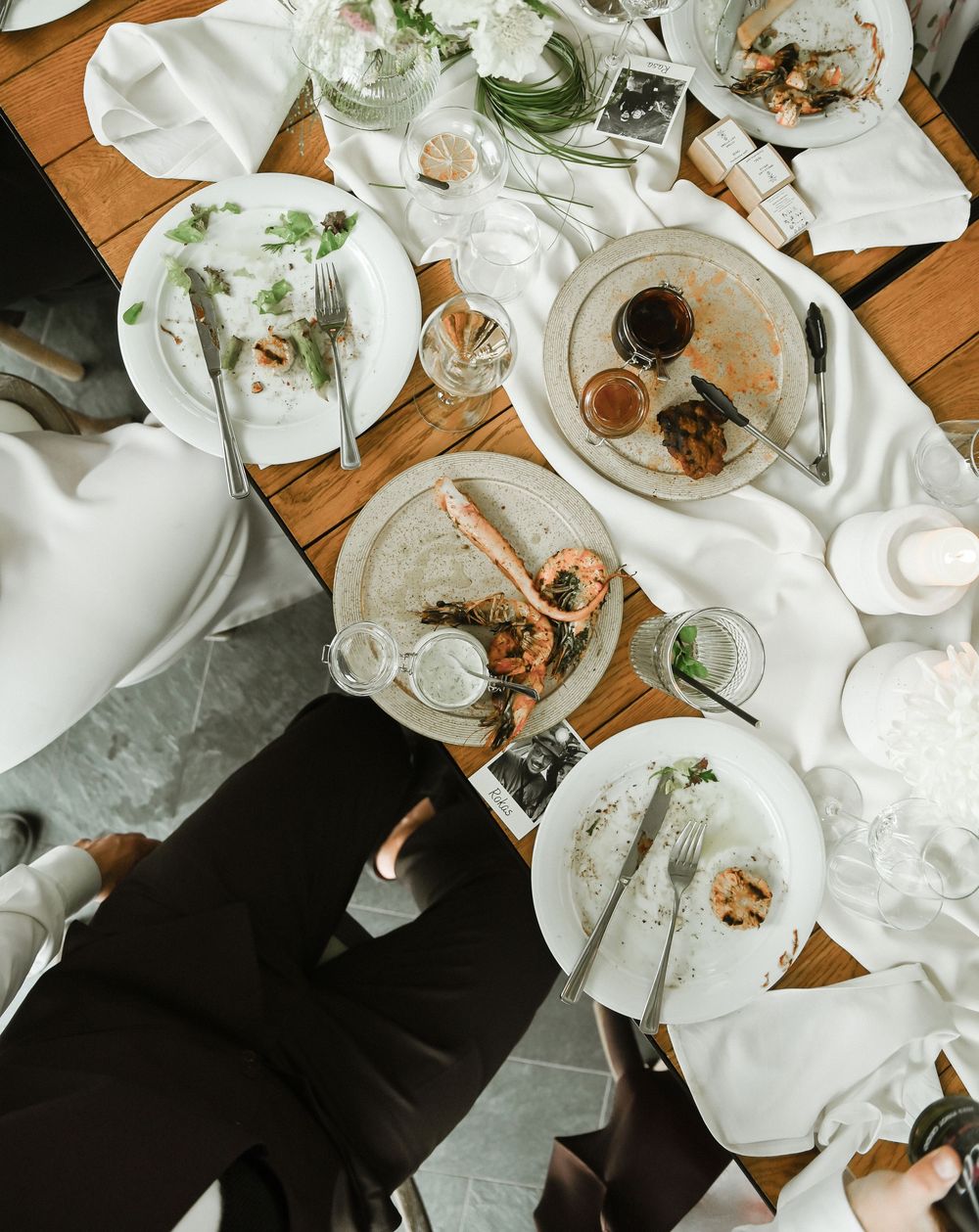 Overhead view of a dining table with white plates and partially eaten food at a reception.