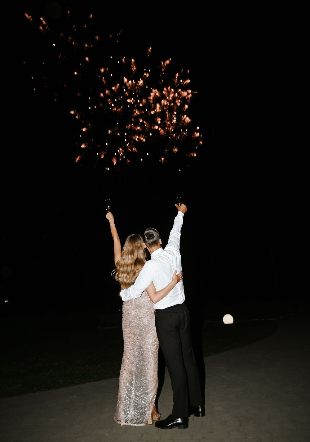 Couple dancing under a shower of orange sparklers creating a magical nighttime celebration atmosphere.