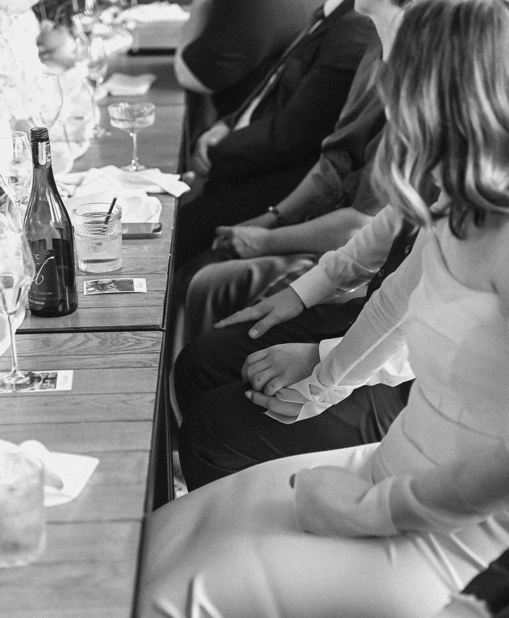 Close-up shot of people sitting at a table with drinks and hands gesturing in conversation.