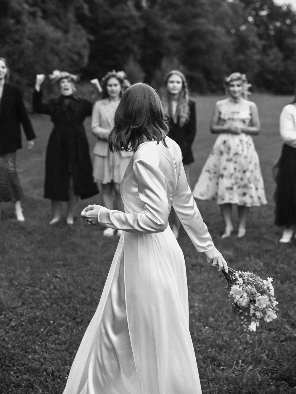 Black and white photo of wedding guests gathered outdoors on a grassy lawn.