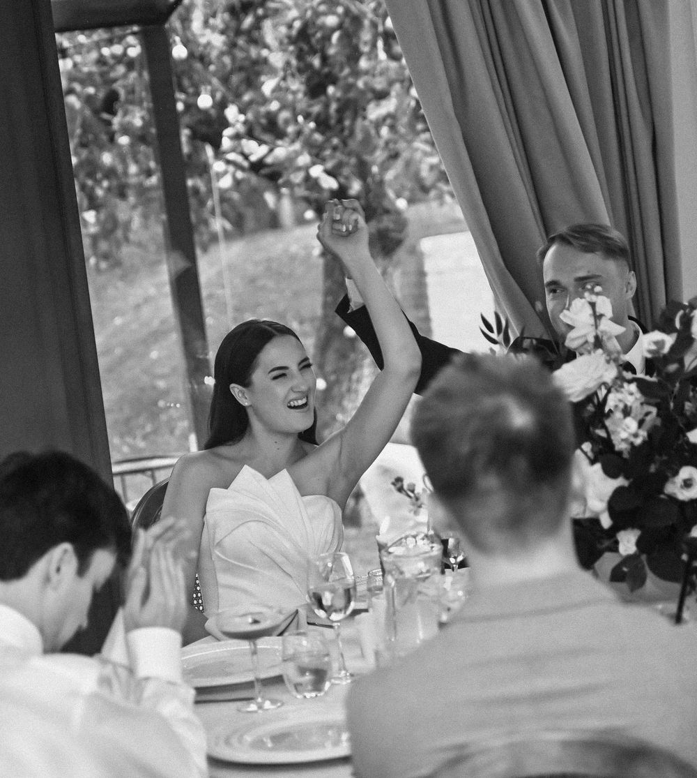 Black and white capture of wedding reception celebration with raised glasses.