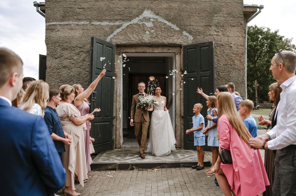 Wedding party exits church while guests celebrate with bubble wands.