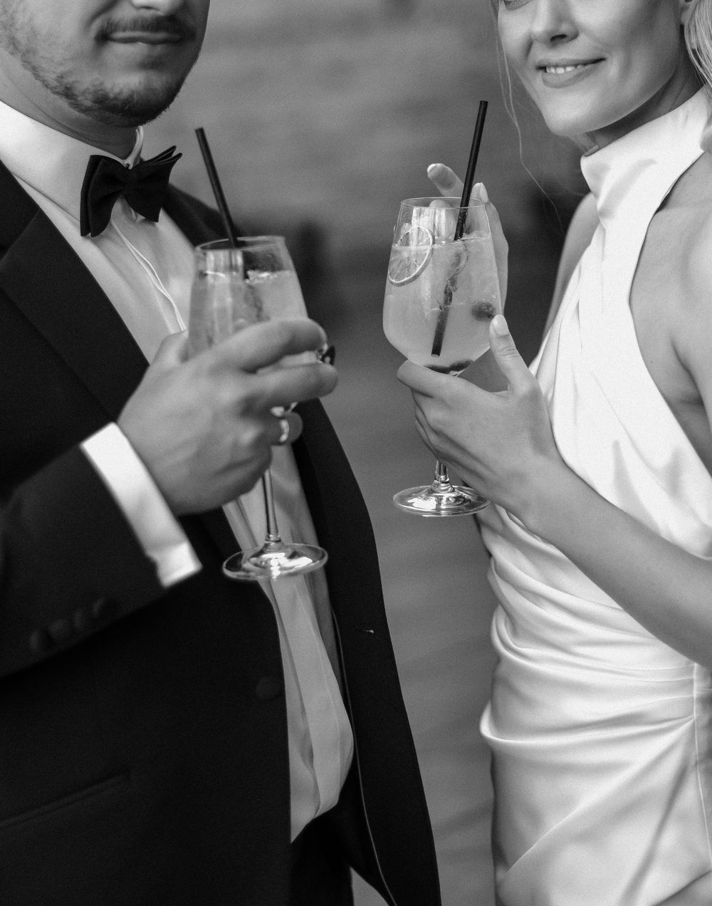 Elegantly dressed couple in formal attire toasting with cocktail glasses at a celebration.