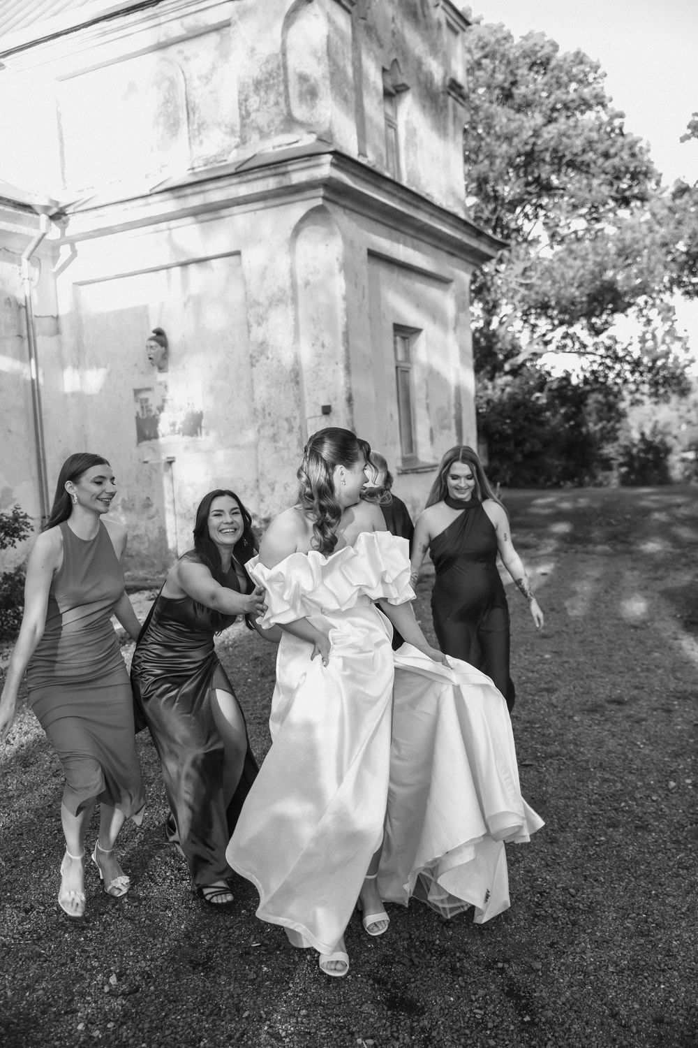 A playful sequence of black and white photos showing a group running and playing on grass near old stone buildings.