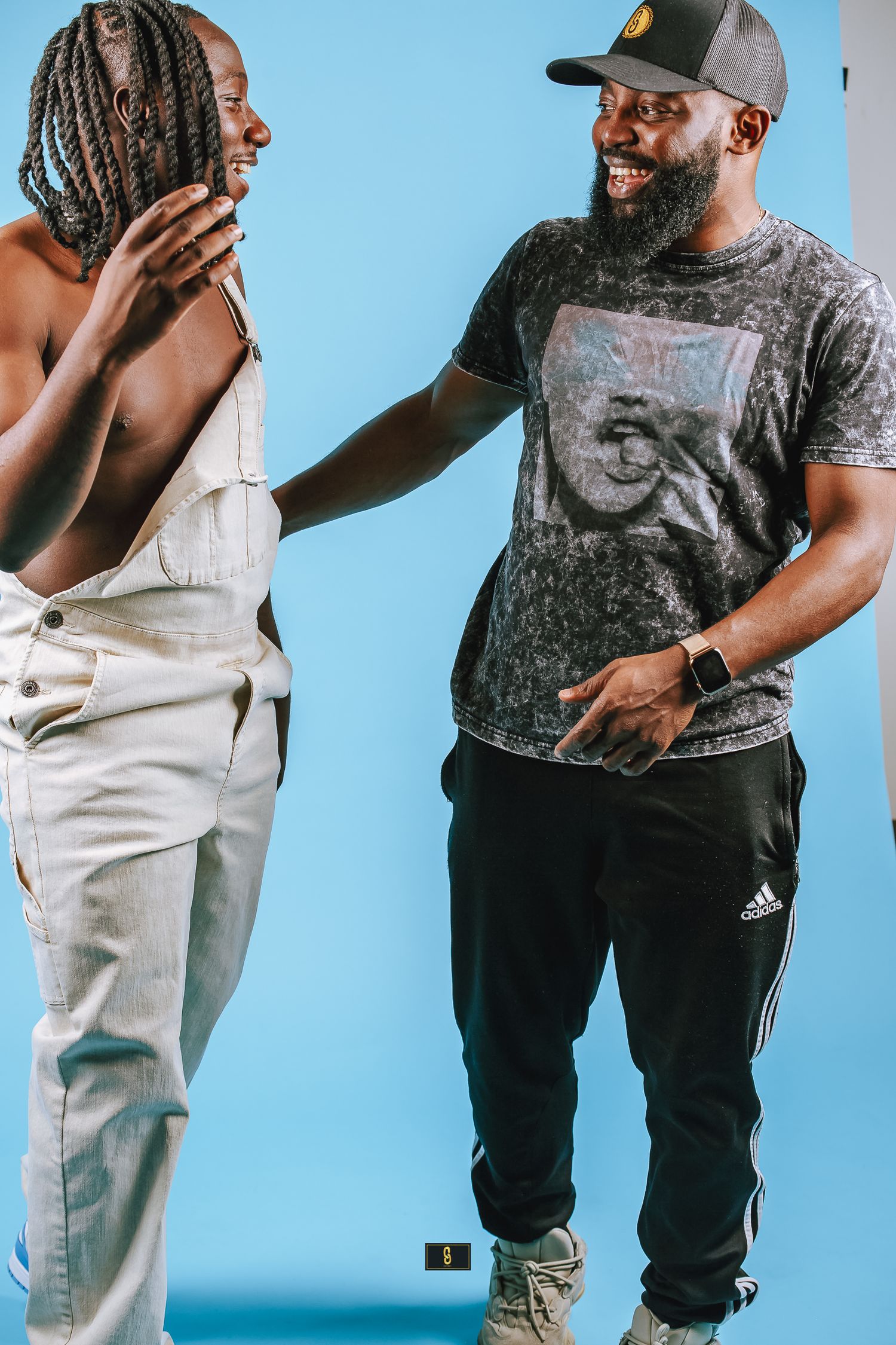 Two friends sharing a candid laughing moment against blue background.