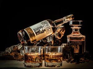 Dramatic side view of Aberfeldy whisky bottles and glasses with golden lighting against dark background.