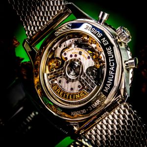 Close-up of a luxury watch movement showing intricate mechanical details with green accent lighting. Luxury product photography.