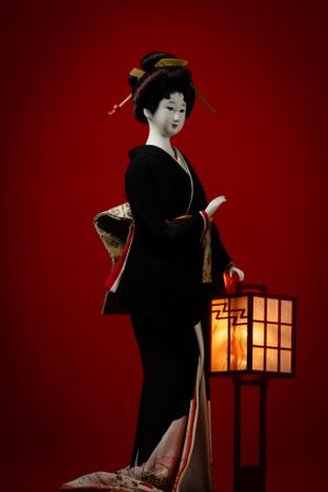 Artistic portrait of geisha doll with traditional clothing and paper lantern. Luxury product photography.