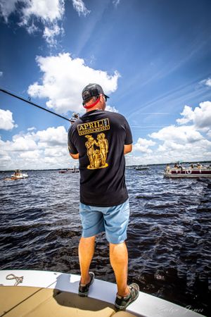 Person wearing a black t-shirt fishing on a boat. Editorial product photography. April One Bourbon Shoot
