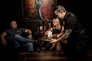 Dark moody bar scene with patrons sitting at tables in dramatic lighting and atmospheric shadows.