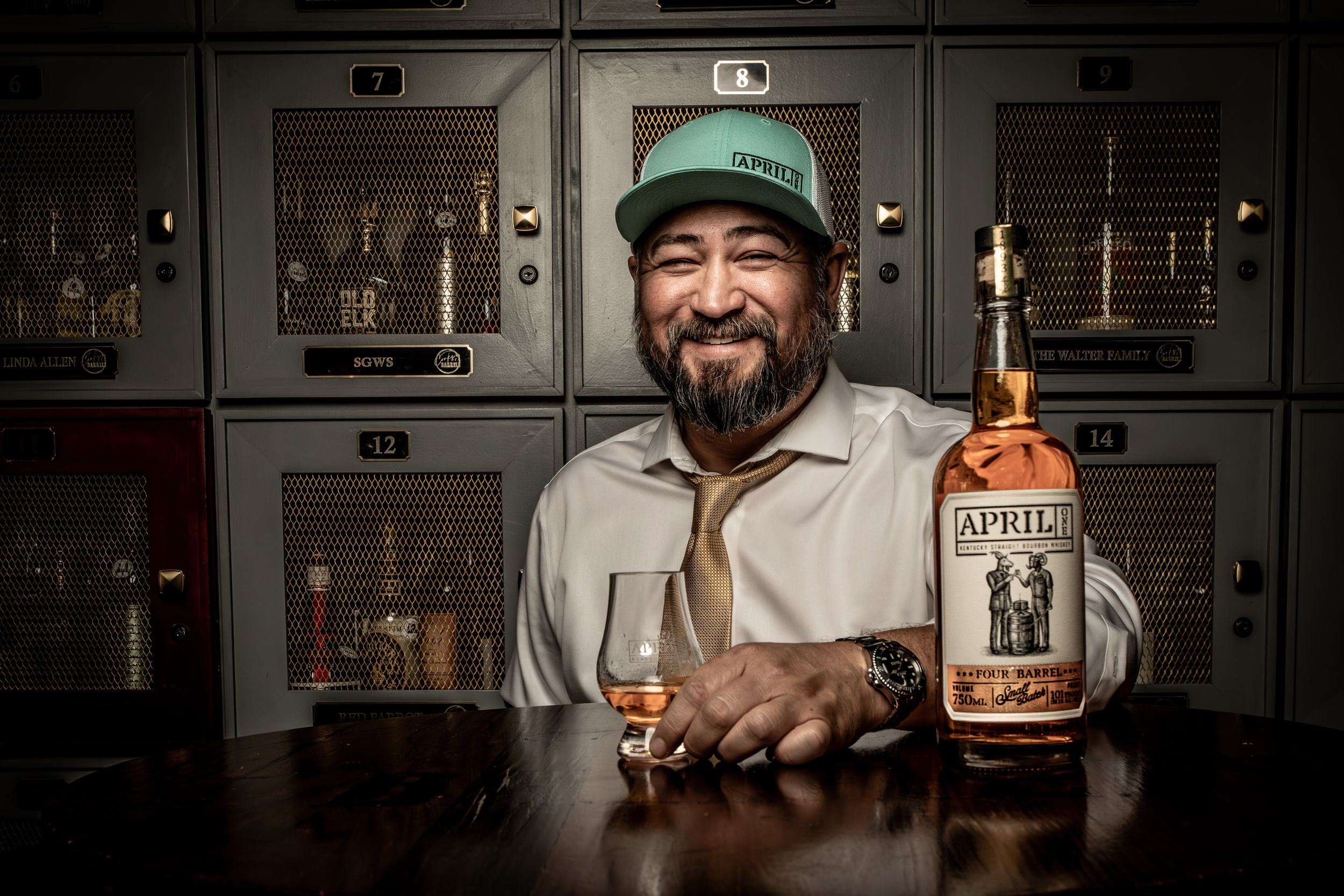 Person holding a bottle of Old Forester bourbon whiskey while smiling in a dimly lit bar setting.