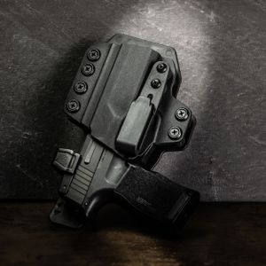 A black Kydex IWB holster for a pistol displayed on dark wooden surface. Product photography.