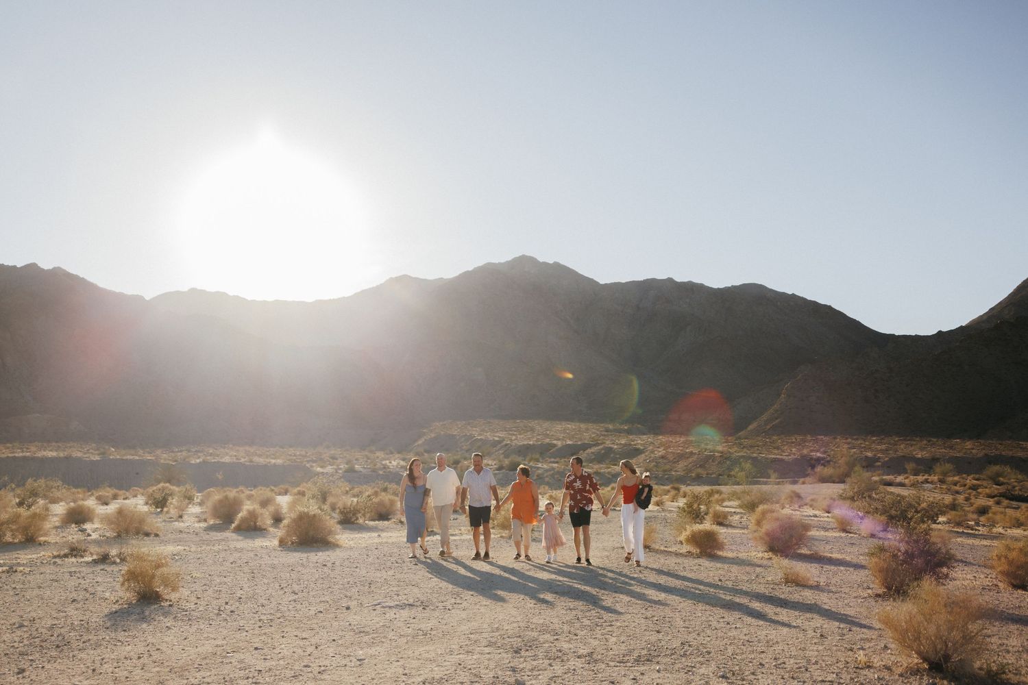 Group of friends walking together in a sunny desert landscape with mountains in the background.